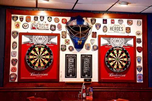A wall decorated with dartboards, badges, and memorabilia in a cozy bar setting.