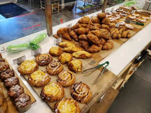A display of various baked goods, including croissants, pastries, and muffins, arranged on a countertop.