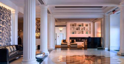 Elegant hotel lobby featuring tall columns, a decorative wall, plush seating, and a stylish marble floor design.