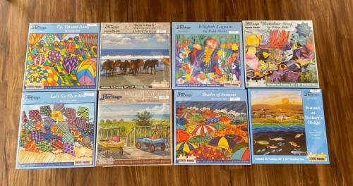 A collection of eight colorful jigsaw puzzle boxes featuring various vibrant landscapes and scenes.