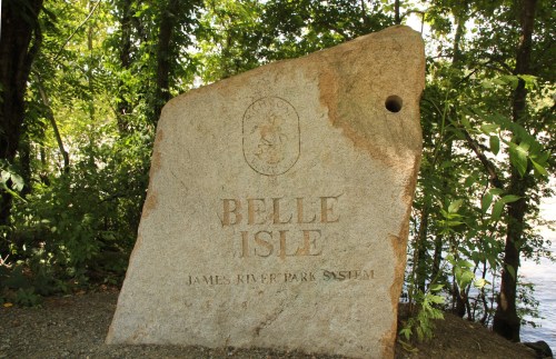 A large stone monument with "BELLE ISLE" and "JAMES RIVER PARK SYSTEM" engraved, surrounded by greenery.