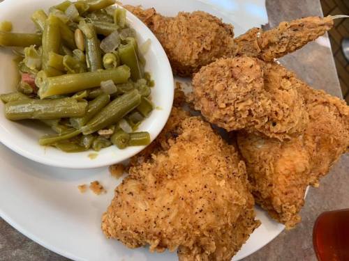 A plate of crispy fried chicken pieces served with a side of green beans.
