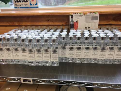 A shelf filled with clear bottles of hand sanitizer, each labeled and neatly arranged in a store.