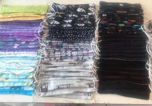 A collection of colorful fabric face masks neatly arranged in rows on a table.