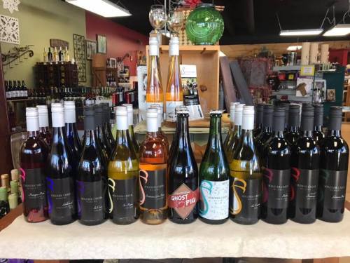 A display of various wine bottles arranged on a table in a store, showcasing different colors and labels.