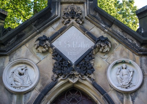 Gothic-style mausoleum with decorative stonework, featuring reliefs and an inscription reading "L. Schlaeber 1892."