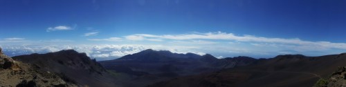 Panoramic view of a mountainous landscape under a clear blue sky with scattered clouds.