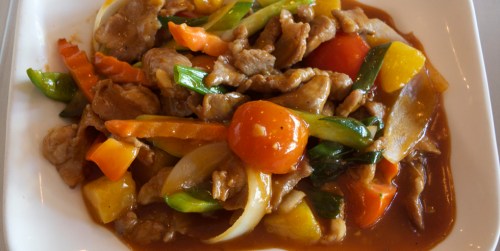 A colorful dish of stir-fried meat and vegetables in a savory sauce, served on a white plate.