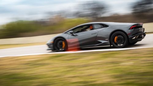 A sleek gray sports car speeds around a racetrack, showcasing its dynamic design and motion blur.