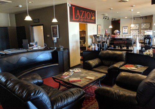Cozy coffee shop interior with black leather seating, a coffee bar, and a welcoming atmosphere.