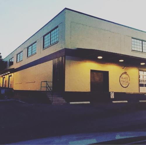 A large, industrial-style building with a sign reading "Black Circle," illuminated in the evening light.