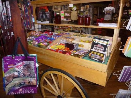 A wooden cart filled with various snacks, candy, and merchandise in a shop setting.