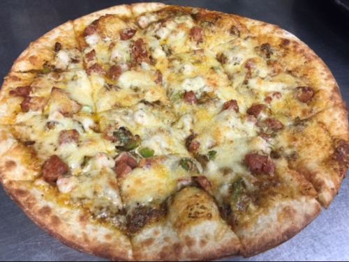 A freshly baked pizza topped with melted cheese, sausage, and green peppers on a golden crust.