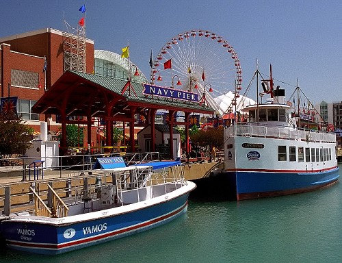 Navy Pier with colorful flags, a ferris wheel, and boats docked in a vibrant waterfront scene.