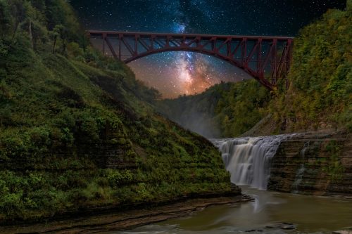 A waterfall flows beneath a red bridge, with a starry sky and the Milky Way visible above the lush, green landscape.