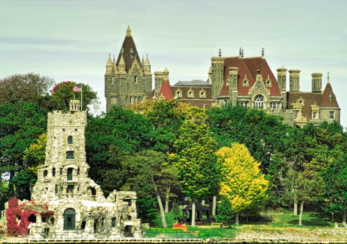 A historic stone castle and a grand mansion surrounded by lush trees and colorful foliage.
