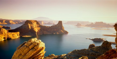 A serene landscape featuring rocky formations and calm waters under a warm sunset sky.