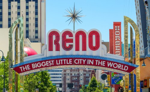 Colorful sign reading "Reno: The Biggest Little City in the World" with a starburst and surrounding buildings.