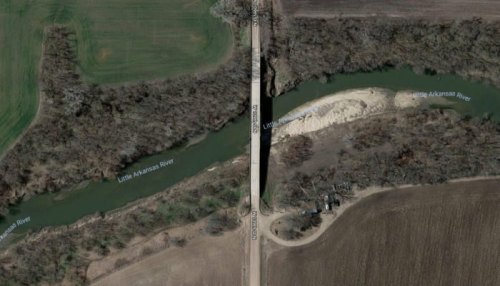Aerial view of a bridge over the Little Arkansas River, surrounded by fields and wooded areas.