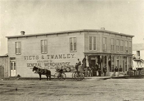 Historic storefront of Viets & Twamley, a general merchandise dealer, with a horse-drawn cart and people outside.
