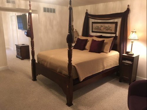 Cozy bedroom featuring a four-poster bed, warm lighting, and elegant decor in soft tones.