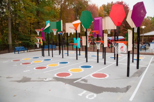 Colorful basketball hoops on a court surrounded by trees, with painted circles and numbers on the ground.