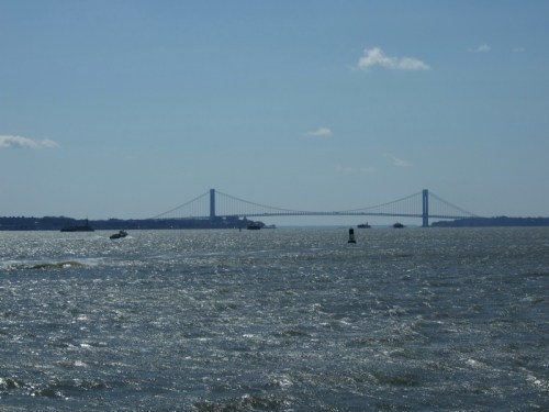 A view of a bridge spanning a body of water, with boats and a clear blue sky in the background.
