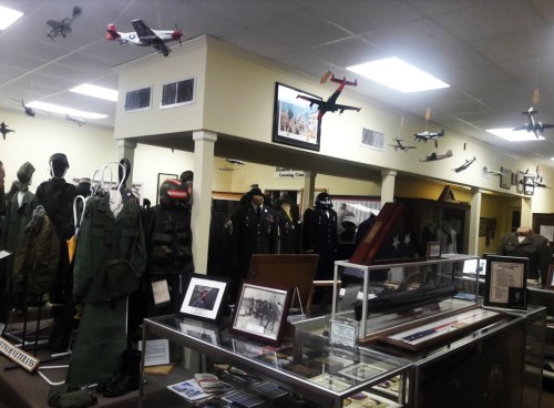A military museum display featuring uniforms, aircraft models, and historical artifacts.