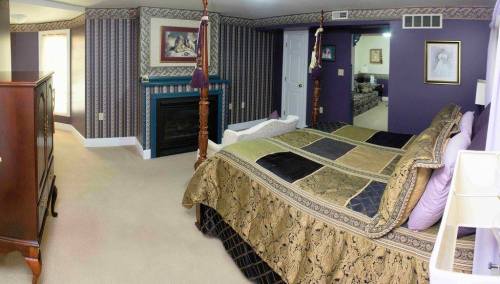 Cozy bedroom with a large bed, decorative bedding, a fireplace, and elegant wallpaper in shades of purple and gold.