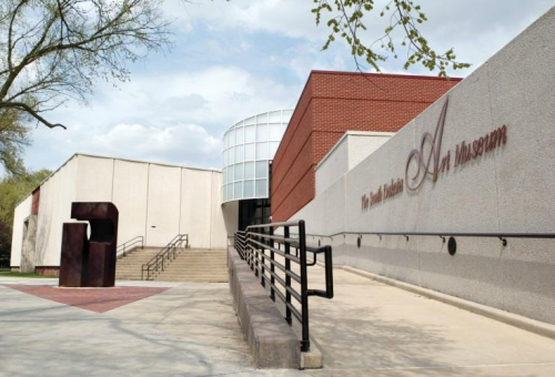 Exterior view of an art museum with a modern design, featuring stairs and a sculpture in the foreground.