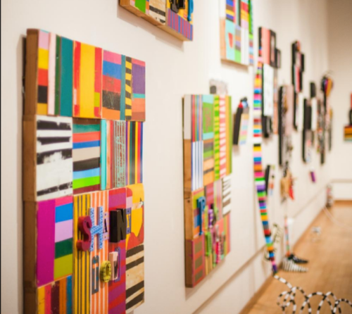 Colorful abstract art pieces with various patterns and textures displayed on a gallery wall.