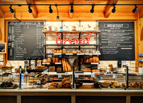 A cozy café display featuring various breads, pastries, and a menu board in a wooden interior.