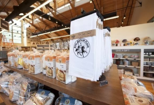 A display of King Arthur Flour products, including bags of flour and kitchen towels, in a well-lit store.