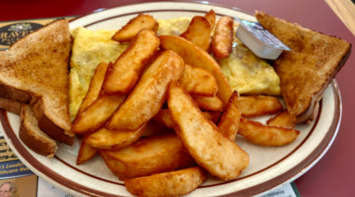 A plate with an omelet, golden potato wedges, and two slices of toasted bread.