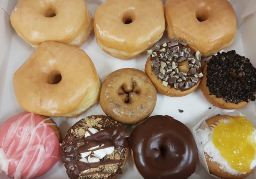 A box of assorted donuts, including glazed, chocolate, and frosted varieties, arranged neatly.