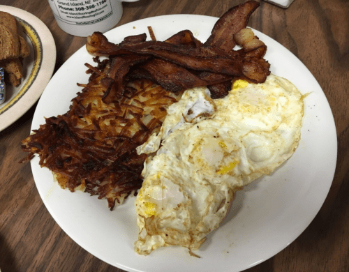 A plate of breakfast featuring fried eggs, crispy bacon, and golden hash browns.