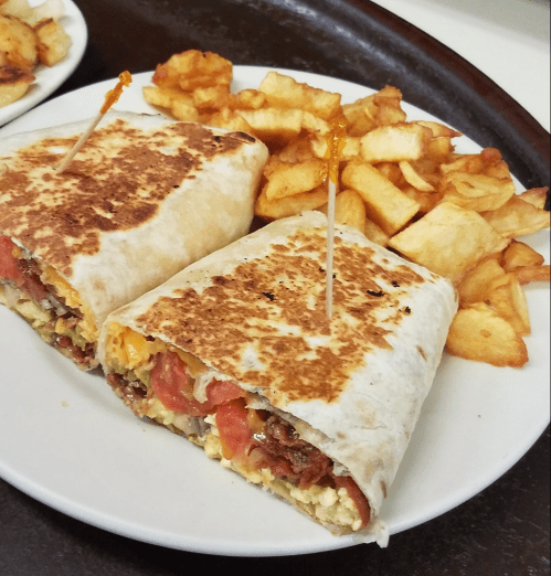 A plate with two toasted burritos filled with vegetables and cheese, served with golden fries on the side.