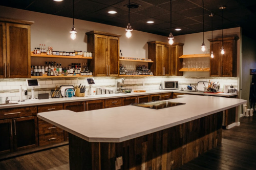 Modern kitchen with wooden cabinets, a large island, and pendant lights, featuring various kitchen appliances and utensils.