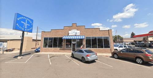 Exterior view of Boonzaaijer's Dutch Bakery, a brick building with large windows and a blue sign, surrounded by parked cars.