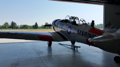 A vintage military aircraft parked in a hangar, with a clear view of its colorful fuselage and wings.