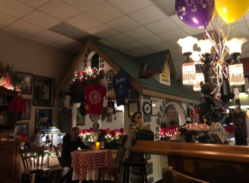 Cozy restaurant interior with a whimsical house facade, festive decorations, and a couple dining at a table.