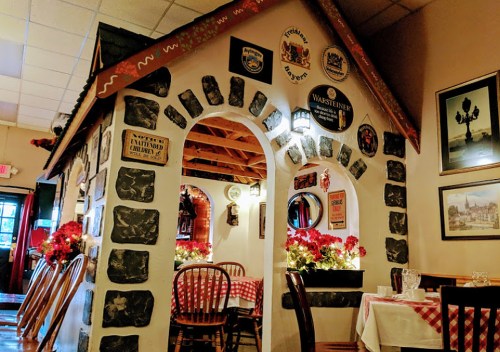 Cozy restaurant interior featuring a stone archway, wooden chairs, and decorative signs on the walls.