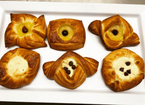 A platter of six assorted pastries with fruit fillings, featuring golden-brown flaky crusts.