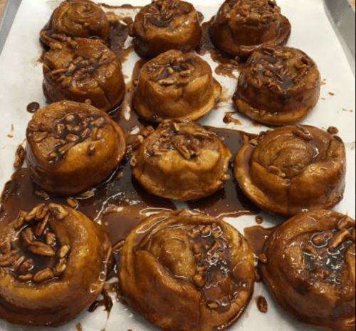 A tray of freshly baked sticky buns topped with pecans and caramel glaze.