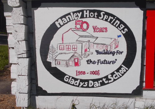 Sign celebrating 50 years of Manley Hot Springs Gladys Dart School, featuring a building illustration and the years 1958-2008.