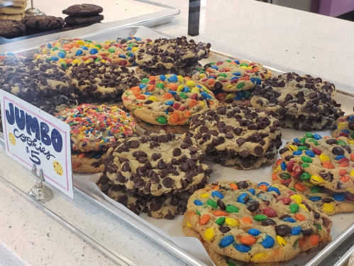 A tray of colorful jumbo cookies topped with chocolate chips, sprinkles, and candy-coated chocolates.