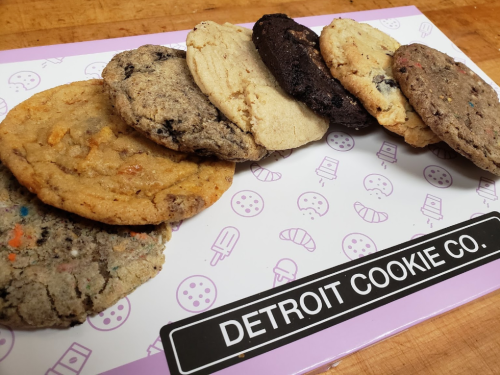 A variety of cookies arranged in a row on a colorful tray, labeled "Detroit Cookie Co."