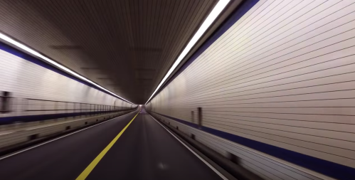 A view of a long, illuminated tunnel with a yellow line down the center, creating a sense of motion and depth.