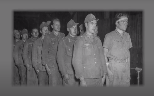 A line of soldiers in uniform, standing in a dimly lit space, looking serious and somber.