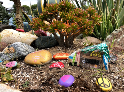 A colorful rock garden featuring painted stones, a succulent plant, and decorative rocks with various designs.
